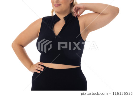 Caucasian plus-size young woman in black sportswear poses confidently on white bg 116136555