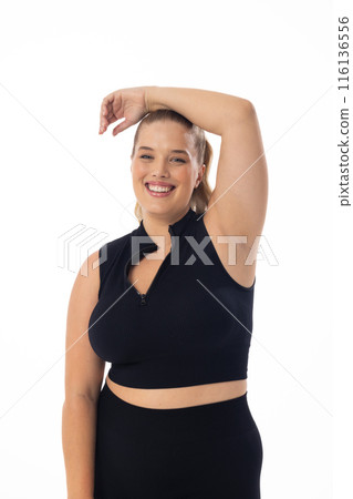 Smiling Caucasian plus-size model poses, hand on head, against white background Smiling Caucasian plus-size model poses, hand on head, against white background 116136556