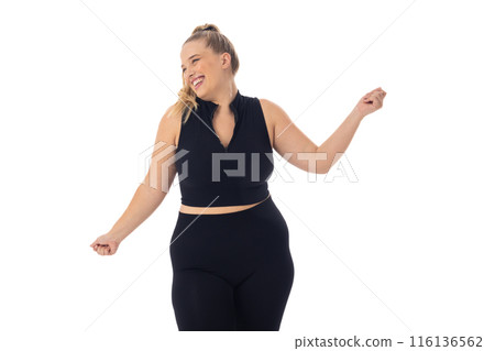 Caucasian plus-size woman in black activewear dances on white background 116136562