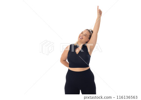 Caucasian plus-size young woman in black sportswear on white, pointing up 116136563