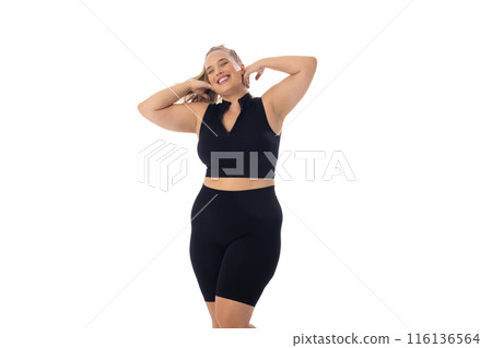 A young Caucasian plus-size model stands on white background, copy space 116136564