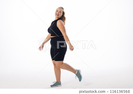 Caucasian young female plus size model on white background is laughing and walking, copy space 116136568