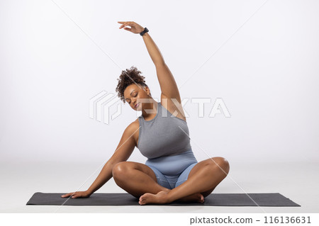 A biracial young female plus size model stretches on white background, copy space A biracial young female plus size model stretches on white background, copy space 116136631