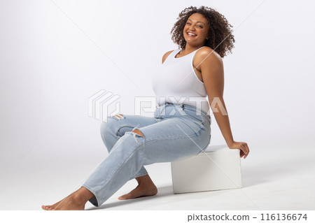 Biracial plus size model sits smiling on white background, copy space Biracial plus size model sits smiling on white background, copy space 116136674
