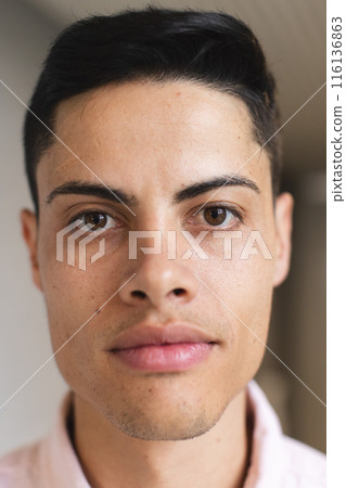 Biracial man with short dark hair looks at camera in modern office 116136863