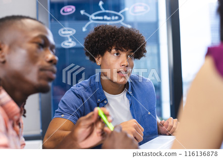 Biracial man with curly hair talks with colleagues in a modern office Biracial man with curly hair talks with colleagues in a modern office 116136878