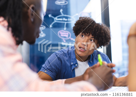 Diverse group of colleagues discussing, sitting around a table in a modern business office 116136881