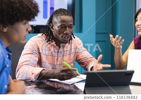 Diverse colleagues discuss around tablet in a modern office 116136882