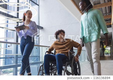 Diverse colleagues walking and talking in bright hallway in a modern business office Diverse colleagues walking and talking in bright hallway in a modern business office 116136894