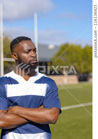 African American young male athlete standing with arms crossed on rugby field, copy space African American young male athlete standing with arms crossed on rugby field, copy space 116136925