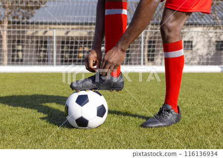 An African American young male athlete tying his shoelaces on soccer field An African American young male athlete tying his shoelaces on soccer field 116136934
