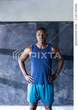 Confident African American athlete and fitness model stands in gym, hands on hips Confident African American athlete and fitness model stands in gym, hands on hips 116136946