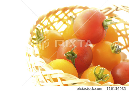 A bamboo basket full of yellow and red cherry tomatoes photographed on a white background 116136983