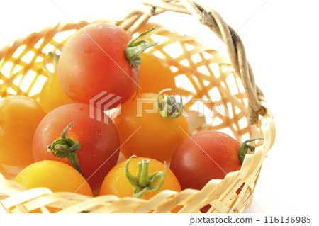 A bamboo basket full of yellow and red cherry tomatoes photographed on a white background A bamboo basket full of yellow and red cherry tomatoes photographed on a white background 116136985