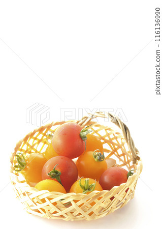 A bamboo basket full of yellow and red cherry tomatoes photographed on a white background 116136990