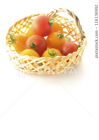 A bamboo basket full of yellow and red cherry tomatoes photographed on a white background A bamboo basket full of yellow and red cherry tomatoes photographed on a white background 116136992