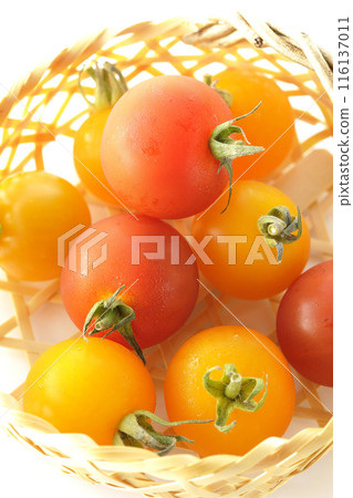 A bamboo basket full of yellow and red cherry tomatoes photographed on a white background A bamboo basket full of yellow and red cherry tomatoes photographed on a white background 116137011