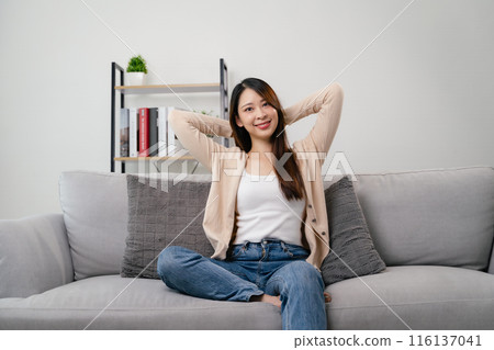 A portrait of beautiful young asian woman is sitting on a couch and smiling. A portrait of beautiful young asian woman is sitting on a couch and smiling. 116137041
