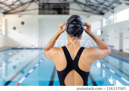Biracial girl adjusts her swim cap, prepping for pool practice 116137065