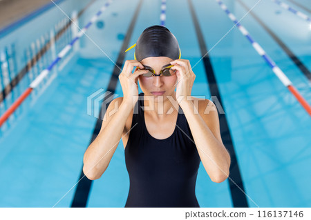 Biracial young female swimmer adjusting goggles at an indoor pool Biracial young female swimmer adjusting goggles at an indoor pool 116137146