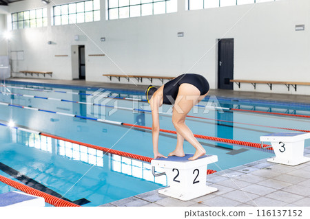 Young biracial female swimmer preparing to dive into an indoor pool, wearing a black swimsuit, copy Young biracial female swimmer preparing to dive into an indoor pool, wearing a black swimsuit, copy 116137152