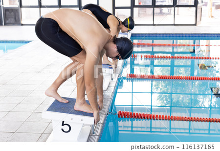 Diverse swimmers, a Caucasian boy and biracial girl, ready to dive 116137165
