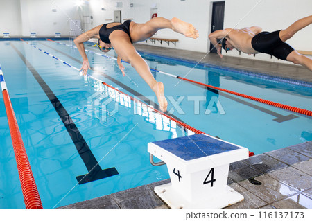 Biracial girl and Caucasian boy dive into pool as swim competitors 116137173