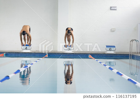 Diverse swimmers, a Caucasian boy and biracial girl, ready to dive into a pool, copy space 116137195