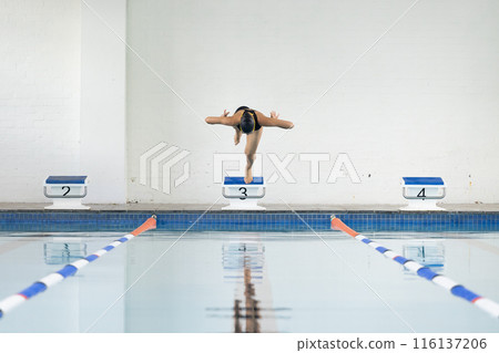 Biracial girl dives into pool, wears black swimsuit, copy space 116137206
