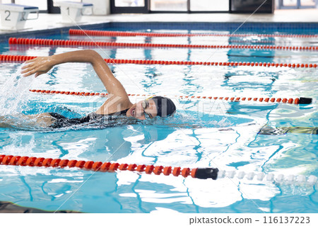 Biracial young female wearing goggles swimming in swimming pool, copy space Biracial young female wearing goggles swimming in swimming pool, copy space 116137223