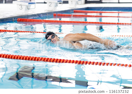 Caucasian young male swimmer with light skin training indoors in swimming pool Caucasian young male swimmer with light skin training indoors in swimming pool 116137232