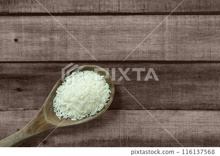 Raw Thai jasmine rice grains on wooden ladle, on wooden floor, angle of view flat lay and top down horizontal view. Raw Thai jasmine rice grains on wooden ladle, on wooden floor, angle of view flat lay and top down horizontal view. 116137568