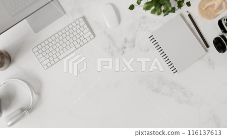 A white marble office desk top view features a computer, headphones, stationery, and a copy space. A white marble office desk top view features a computer, headphones, stationery, and a copy space. 116137613