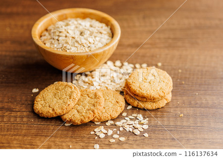 Tasty oatmeal cookies and rolled oat on wooden table. 116137634