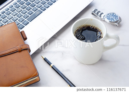 一張圖片:在辦公桌前拿著筆記型電腦和筆記型電腦工作,同時喝著現煮的咖啡。 一張圖片:在辦公桌前拿著筆記型電腦和筆記型電腦工作,同時喝著現煮的咖啡。 116137671