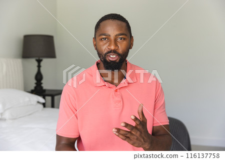African American man standing, talking with hand gesture at home during a video call 116137758