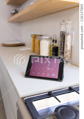 A tablet displaying smart home interface rests on a kitchen counter at home 116137805