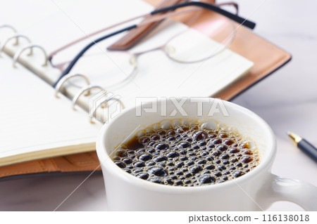 An image of a man drinking freshly brewed coffee, opening his ring-type system organizer, and thinking about how to organize his work. 116138018