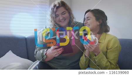 Image of lgbtq over happy caucasian lesbian couple using tablet and sitting on sofa at home Image of lgbtq over happy caucasian lesbian couple using tablet and sitting on sofa at home 116139060