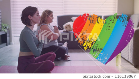 Image of rainbow heart over caucasian lesbian couple practicing yoga at home 116139067