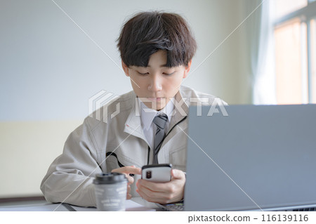 穿著工作服的年輕人觸摸智慧型手機 116139116