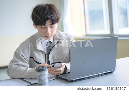 穿著工作服的年輕人觸摸智慧型手機 穿著工作服的年輕人觸摸智慧型手機 116139117