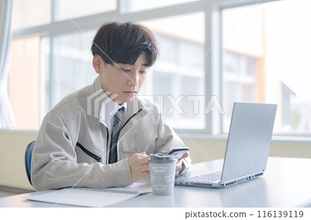 A young man in work clothes touching a smartphone A young man in work clothes touching a smartphone 116139119