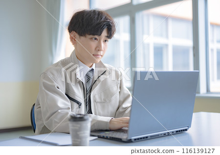 穿著工作服的年輕人在電腦上打字 116139127