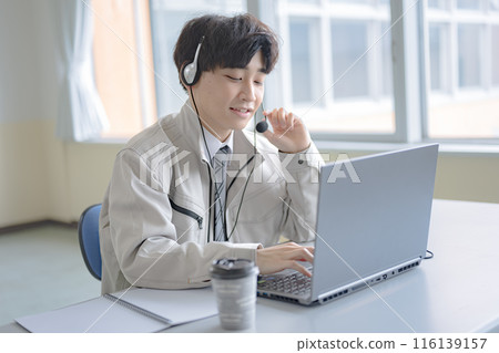 A young man in work clothes wearing an intercom A young man in work clothes wearing an intercom 116139157