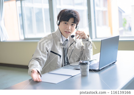 A young man in work clothes wearing an intercom A young man in work clothes wearing an intercom 116139166