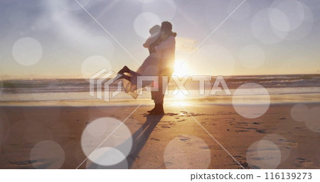 Image of light spots over happy african american groom lifting bride on sunset beach at wedding Image of light spots over happy african american groom lifting bride on sunset beach at wedding 116139273