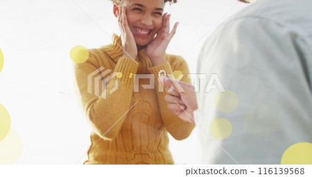 Image of light spots over african american couple proposing on beach 116139568