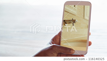 Image of person using smartphone with house bathroom interiors displayed on screen 116140325
