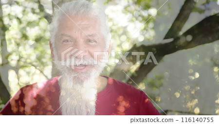 Image of spots of light and trees over smiling senior biracial man in garden 116140755